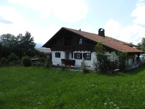 a white house with a brown roof in a field at Ferienwohnung Alpenpanorama in Halblech
