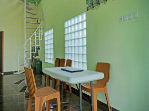 uma sala de jantar com uma mesa branca e cadeiras em OYO 92293 Pahala Syariah Residence em Perabumulih