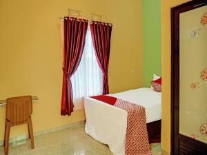 um quarto com uma cama e uma janela com cortinas vermelhas em OYO 92293 Pahala Syariah Residence em Perabumulih