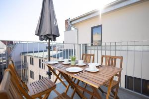 uma mesa de madeira com cadeiras e um guarda-sol numa varanda em Ko-Living - Captain's Suite - Altstadt - mit Küche, Smart TV & Balkon - 6P em Halle an der Saale