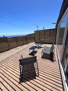 a deck with benches and tables on the beach at Cabaña Hermosa Maitencillo in Valparaíso