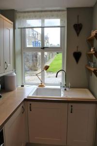 a kitchen with a sink and a window at Caterpillar Cottage, tucked away in Kelbrook in Kelbrook