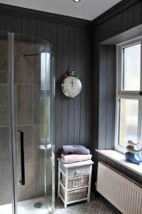 a bathroom with a shower and a clock on the wall at Caterpillar Cottage, tucked away in Kelbrook in Kelbrook