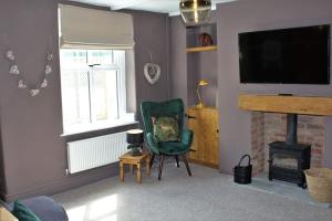 a living room with a green chair and a fireplace at Caterpillar Cottage, tucked away in Kelbrook in Kelbrook