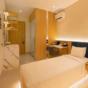 um quarto de hotel com uma cama e uma secretária em The Risman Hotel At Jakarta Airport CBC em Tangerang