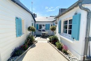 een wit huis met blauwe luiken en een patio bij Cabane du Pêcheur, maison avec extérieur in Le Crotoy