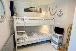Zimmer mit 2 Etagenbetten und einem TV in der Unterkunft Cabane du Pêcheur, maison avec extérieur in Le Crotoy