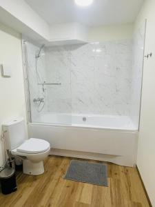 a bathroom with a white tub and a toilet at Alanta Apartments Easy Kaunas in Kaunas