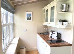 a kitchen with white cabinets and a sink and a window at Coastal Chic waterfront studio in Kinsale