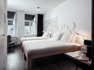 two beds in a room with two windows at MABI City Centre in Maastricht