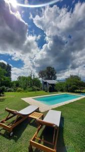 una piscina con 2 tumbonas, una mesa y una piscina en Entre Las Sierras Cabañas en Villa Giardino