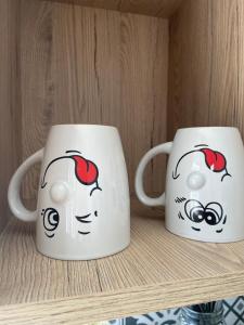 two coffee mugs are sitting on a shelf at « Le Petit Louis » in Briord