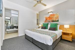 a bedroom with a large bed with green pillows at 9408 Luxury Apartment Close to Hastings Street in Noosa Heads