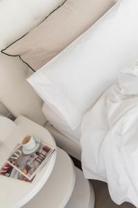 a bed with white sheets and a magazine on a table at El Palauet Royal Suites in Barcelona