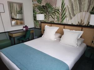 a bedroom with a large bed with white pillows at H&ocirc;tel Paris Neuilly in Neuilly-sur-Seine