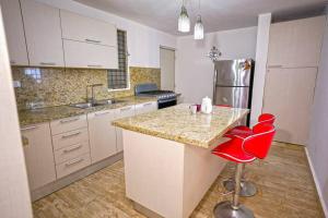 a kitchen with a counter and red chairs in it at Luxurious 3BR House with Private Parking in Santiago de los Caballeros