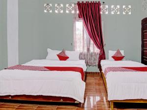 Bangkinang的住宿－OYO 92302 Salsa Homestay Syariah，一间卧室设有两张床,窗户配有红色窗帘