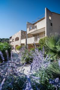 un bâtiment avec des fleurs violettes devant lui dans l'établissement Villages Clubs du Soleil - LE REVERDI, à Grimaud