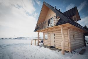 a wooden cabin with a balcony in the snow at Domek pod lasem in Klikuszowa