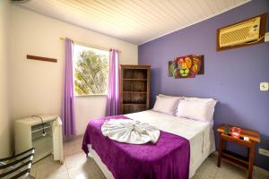 - une chambre avec des murs violets et un lit avec une couverture violette dans l'établissement Pousada Cantinho do Sossego Paraty, à Parati