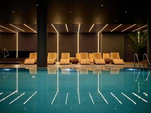 a group of chairs sitting next to a swimming pool at AC Hotel by Marriott Krakow in Kraków