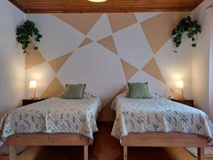 a room with two beds and two lamps on the wall at Mojo House in Ribeira Grande