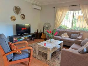 a living room with a couch and a tv at Bougainvillea House in Bijilo