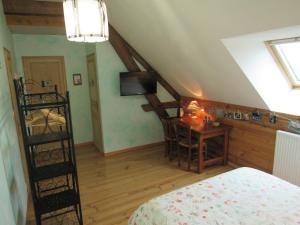 a bedroom with a bed and a desk with a television at Chambres d'hôtes Les Arondelles in Virey-le-Grand