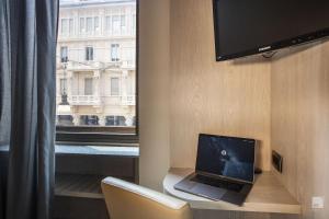 un computer portatile seduto su una scrivania accanto a una finestra di Hotel Diplomatic a Torino