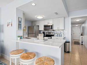 a kitchen with white cabinets and a counter with stools at LR 309 - Ms, Annies Oasis in Rockport