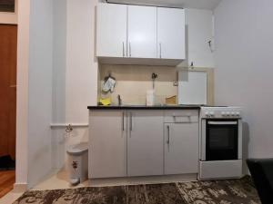 a kitchen with white cabinets and a sink and a stove at Departure Apartment in Sarajevo