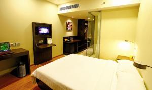 a hotel room with a bed and a television at Keys Select by Lemon Tree Hotels, Hosur Road, Bengaluru in Bangalore