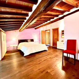 a bedroom with a large bed and a red chair at La Dimora nel Corso in Montepulciano