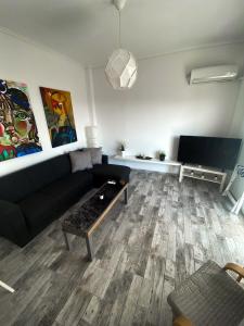 sala de estar con sofá negro y TV en EMVI APARTMENTS III seaview near airport, en Artemida