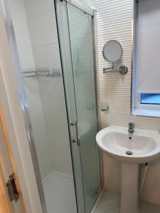 uma casa de banho com uma cabina de duche em vidro e um lavatório. em Flat in Luton Town Centre em Luton