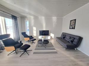 - un salon avec un canapé noir et des chaises dans l'établissement ALEX - bright, stylish apartment with sauna, built in 2023, à Närpiö