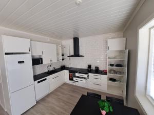 a white kitchen with black counter tops and white appliances at ALEX - bright, stylish apartment with sauna, built in 2023 in Närpiö