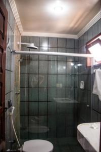 a bathroom with a shower with a toilet and a sink at Hotel Pousada Mahon Mar in Praia do Frances