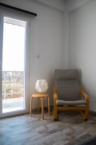 a chair and a table in a room with a window at EMVI APARTMENTS III seaview near airport in Artemida
