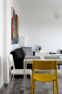 a dining room with a table and yellow chairs at EMVI APARTMENTS III seaview near airport in Artemida