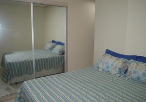 1 dormitorio con espejo junto a la cama en Edifício Corte Real, en Guarapari