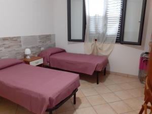 マリーナ・ディ・ラグーザにあるL'Ulivo di Luの紫のシーツが備わる客室内のベッド2台