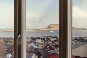een raam met uitzicht op de stad bij New Aparthotel / Panoramic sea view in Tórshavn