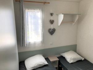 um pequeno quarto com 2 camas e uma janela em Mobil home 4 personnes Plein cœur de la Vendée proche Parc du PUYDUFOU em La Boissière-de-Montaigu