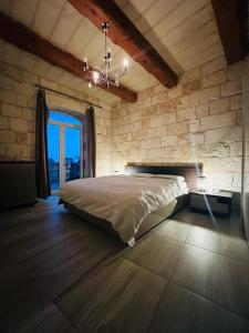a bedroom with a bed and a stone wall at Id-dar Taz-zija Holiday Home including pool & garden in Siġġiewi