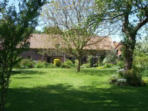 une maison dotée d'une cour avec de l'herbe verte et des arbres dans l'établissement Gite Le Rucher, à Rumegies