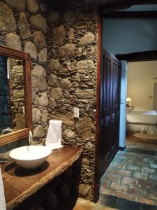 Baño de piedra con lavabo y pared de piedra en Finca El Recreo en Cafayate