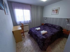 una camera da letto con un letto viola e due asciugamani di Hostal Residencia Taray a Segovia