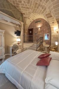 a large white bed in a room with a stone wall at Kelina Charme Hotel by Cantine Due Palme in Cellino San Marco