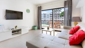 Una sala de estar con un sofá blanco y un televisor. en Sweet As by LovelyStay, en Quarteira